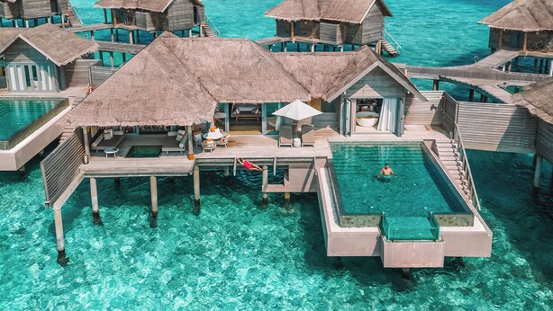 Des bungalows sur pilotis dotés de piscines à débordement, d’une eau turquoise cristalline et offrant une vue sur l’océan.