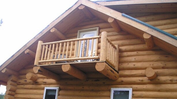 A log cabin with a balcony and two windows.
