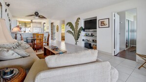 A living room with a sofa, a coffee table, a TV, and a ceiling fan.