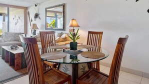 A dining area with a glass table, wooden chairs, and a central potted plant.