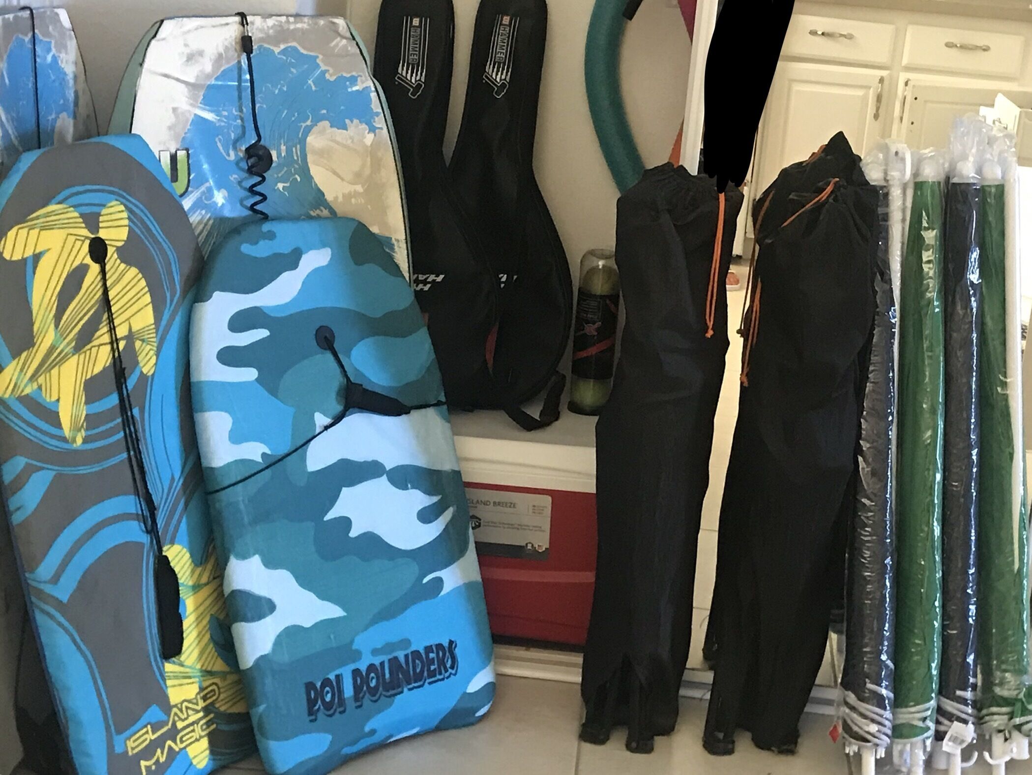 Un espace de rangement contenant divers articles, notamment un sac à motifs de camouflage, des combinaisons de plongée noires et une planche de surf.