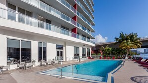 A modern hotel with a rooftop pool, outdoor seating, and a view of the city skyline. - New luxurious 3bdr condo at BW with Resort amenities & Beach Chairs  (Hallandale Beach)