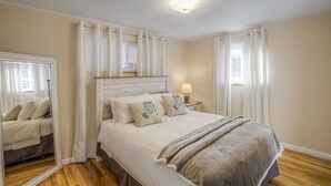 Een slaapkamer met een bed, nachtkastje, spiegel en kamer met patroon.