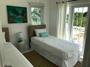 Une chambre à coucher avec un lit, une table de chevet, une lampe, un tableau et une vue sur l’extérieur.
