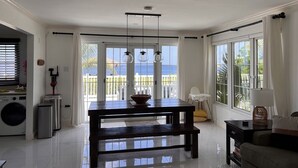 Un vaste espace de vie comprenant une table à manger, un canapé et une vue sur la mer grâce à de grandes fenêtres.