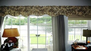 Ein Zimmer mit Seeblick, ein Tisch mit einer Lampe und ein Stuhl am Fenster.