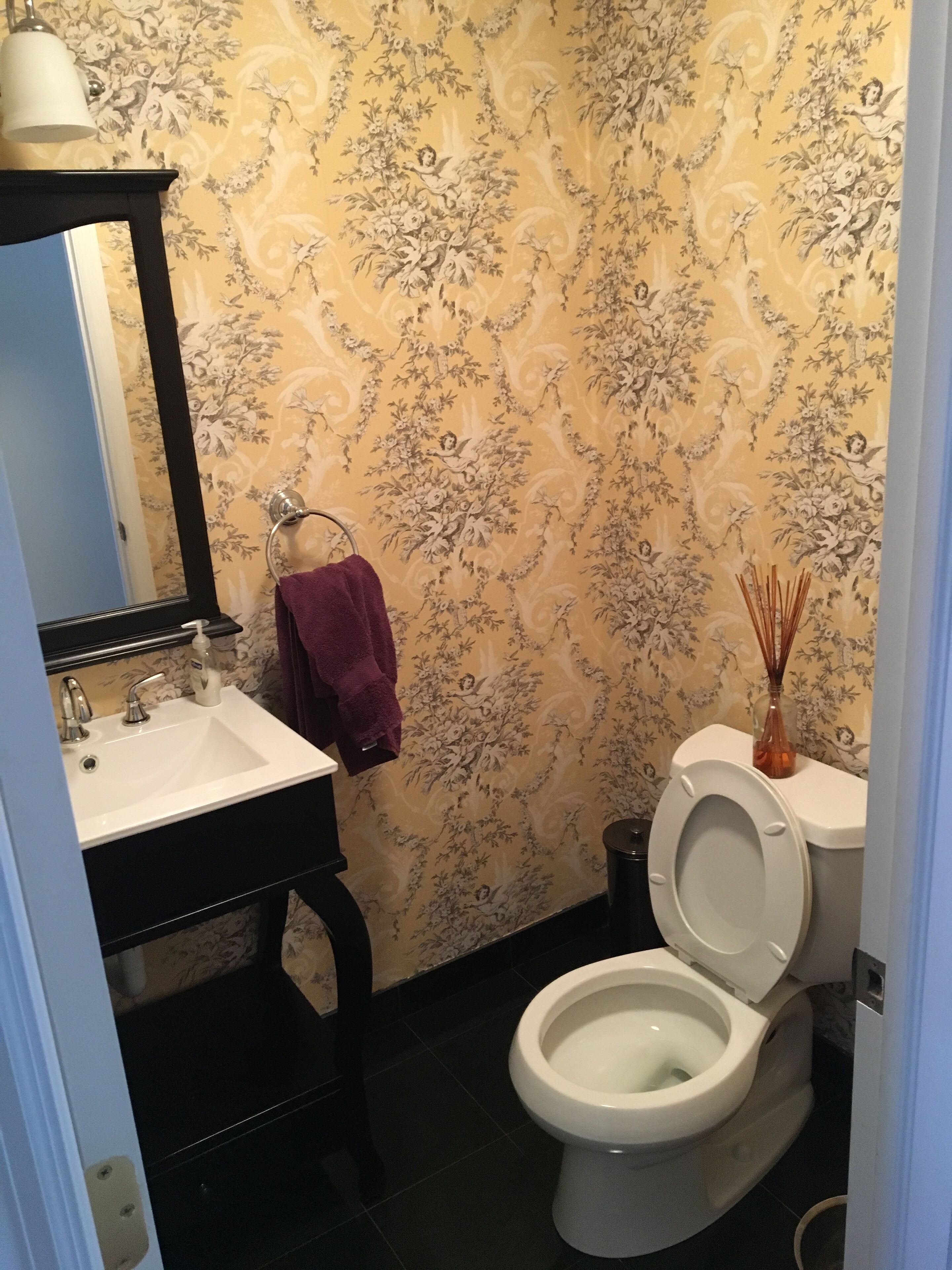 A bathroom with a white sink, a mirror, a toilet, and a towel rack.