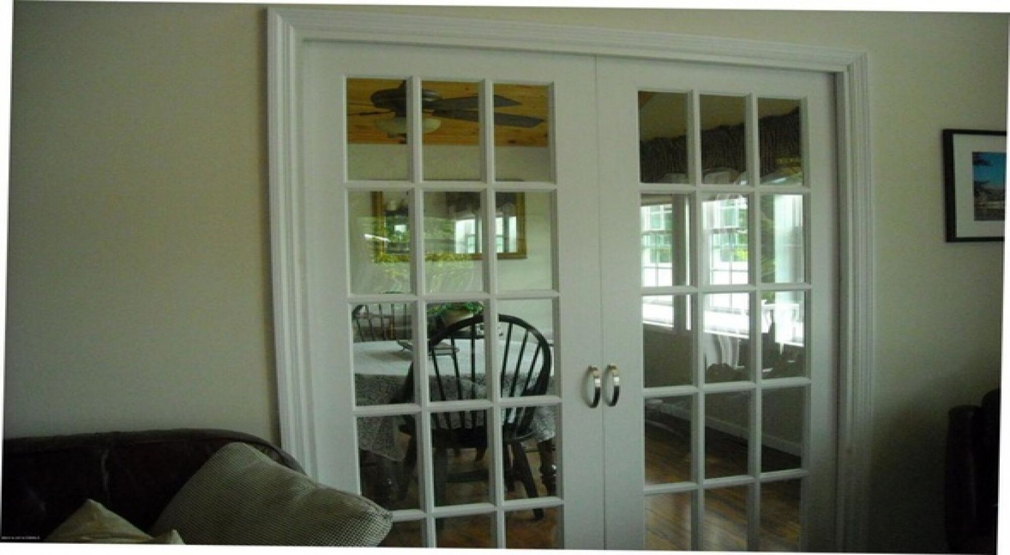 A white-framed glass door with a view of a dining area.