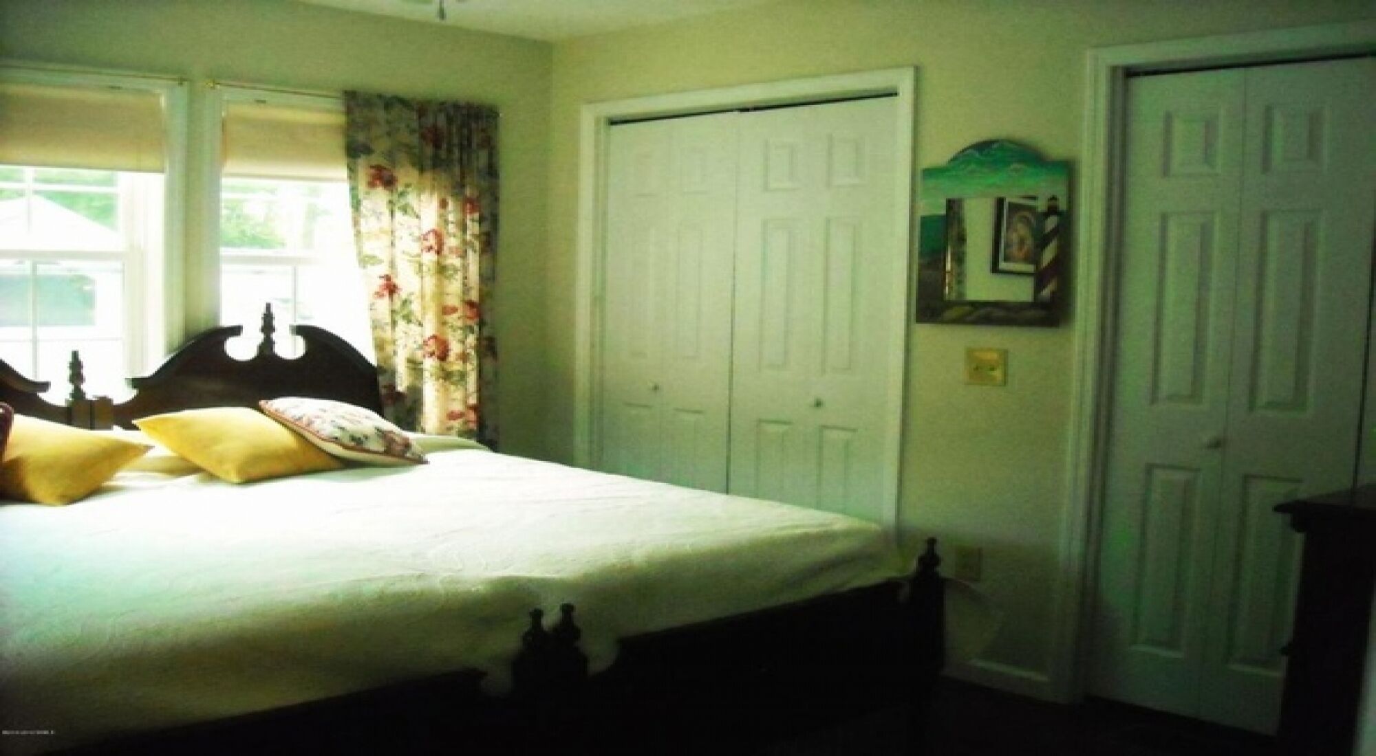 Une chambre à coucher avec un lit, une armoire et un miroir au mur.