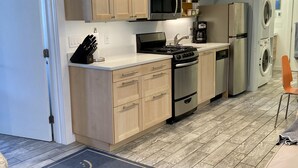 A modern kitchen with wooden cabinets, a gas stove, a microwave, a coffee maker, and a refrigerator.