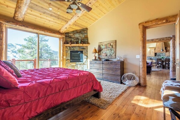 Un dormitorio amplio con una cama grande, una chimenea de piedra y vistas al exterior.