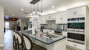 A modern kitchen with a granite countertop, stainless steel appliances, and white cabinetry. - Lakefront/Pool & Hot Tub/NEW PICKLEBALL/Sand Volley Ball/4 acres/Sleeps 28 (Austin)