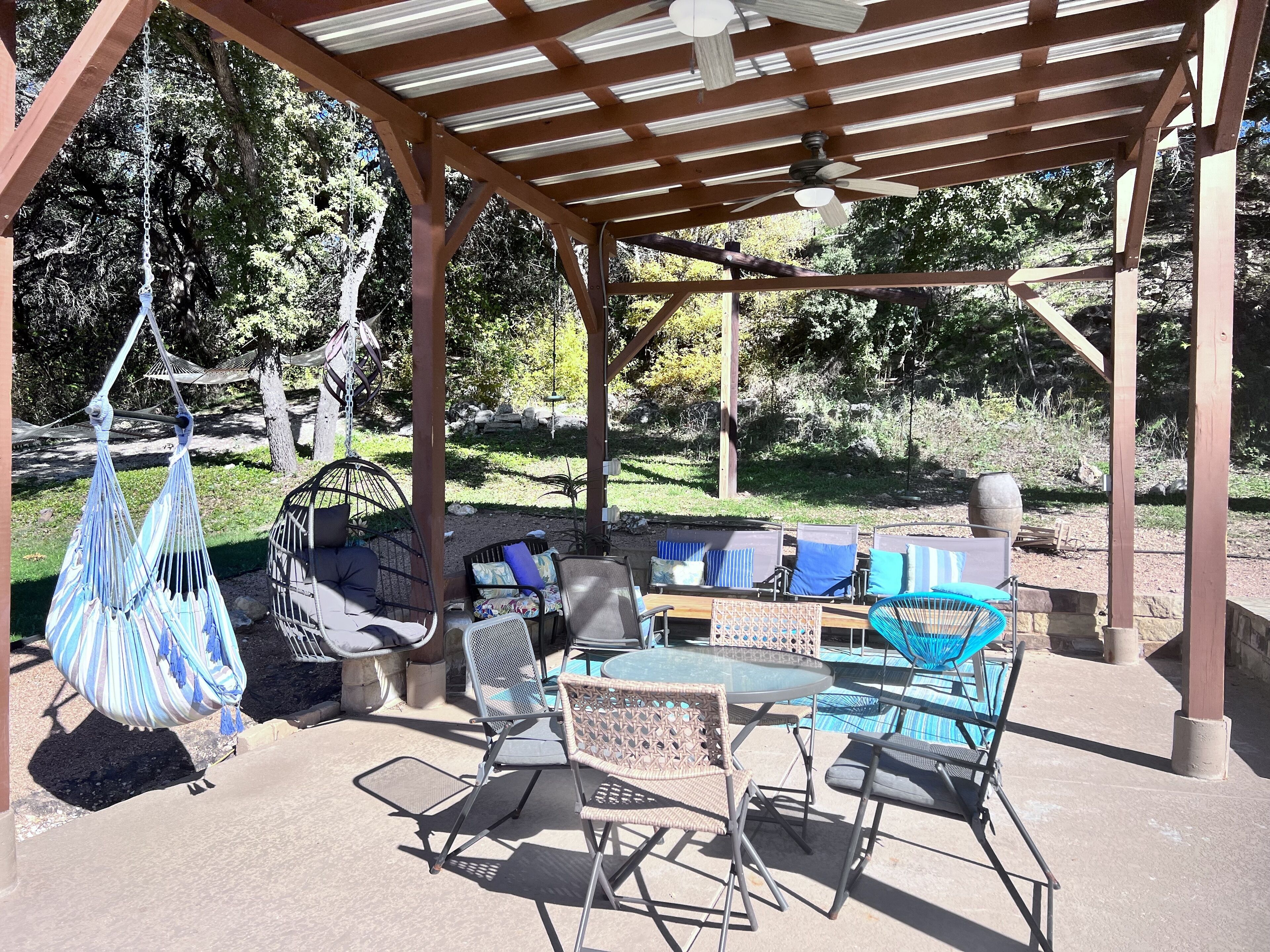 A covered outdoor seating area with a pool, chairs, and a hanging hammock.