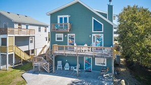 A two-story house with a balcony, a staircase, and a porch area with chairs and a swing.