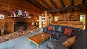 A cozy log cabin interior with a fireplace, leather sofa, bookshelves, and a wooden ceiling. - Reillys Rest-private home in Green Mtns, kid-pet friendly-Ski,Bike,Walk,Relax! (Weston)