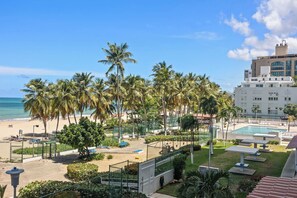 A resort with a pool, palm trees, and a view of the beach.