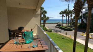 Ein Balkon mit Tisch und Stühlen, der auf eine Straße und ein Gewässer blickt.