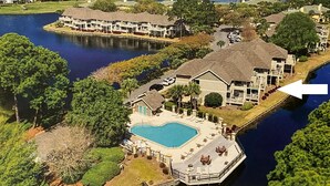 Un quartier résidentiel avec une grande maison dotée d’une piscine, d’un quai et offrant une vue sur l’eau.
