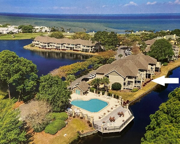 A residential area with a large house featuring a swimming pool, a dock, and a view of the water. - Casual, clean, comfy, beautiful views. Golf cart with agreement. Love your stay. (Miramar Beach)