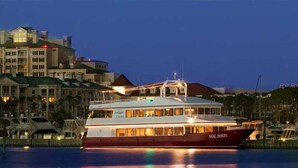 Un grand bateau à plusieurs ponts, sur lequel on peut lire le mot « SOLARIS » sur le côté, est amarré dans une marina, avec des bâtiments en arrière-plan.