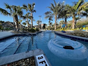 En swimmingpool med klart vand, omgivet af palmer og en klippeformation med teksten "3FT".