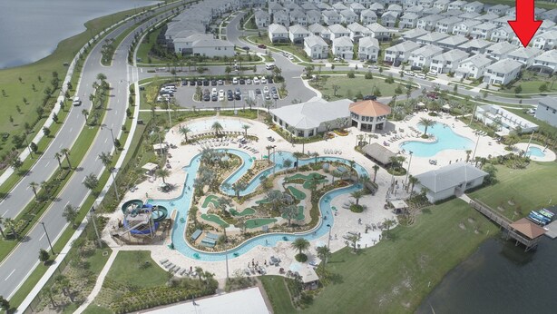 Vue aérienne d’un quartier résidentiel avec une grande piscine, un terrain de golf et un terrain de basketball.