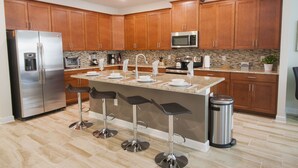 Une cuisine moderne avec des meubles en bois, des appareils en acier inoxydable et un îlot central doté de tabourets de bar.