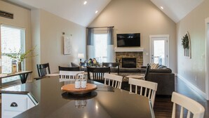 Un salón amplio con chimenea, un comedor con una mesa grande y una cocina visible al fondo.