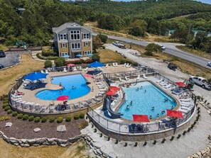 Ein Resort mit zwei Schwimmbecken, einem großen Gebäude und einer Straße im Hintergrund.