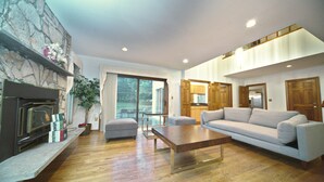 A spacious living room with a fireplace, a sofa, a coffee table, and a view of the outdoors. - Nice Quiet Family Home (Potomac)