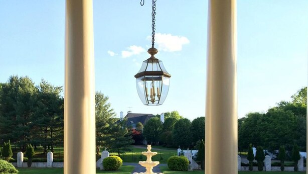 A garden with a central fountain, surrounded by manicured hedges and trees, under a hanging lantern. - Nice Quiet Family Home (Potomac)