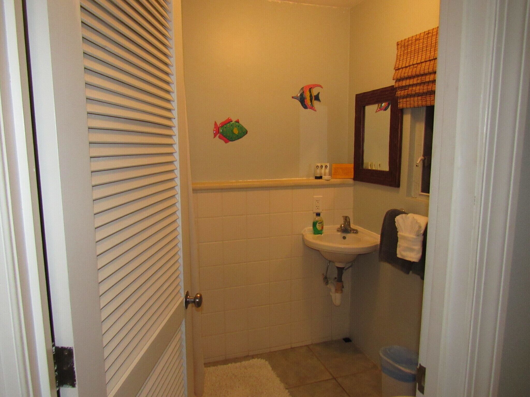 A bathroom with a sink, mirror, and decorative fish wall stickers.