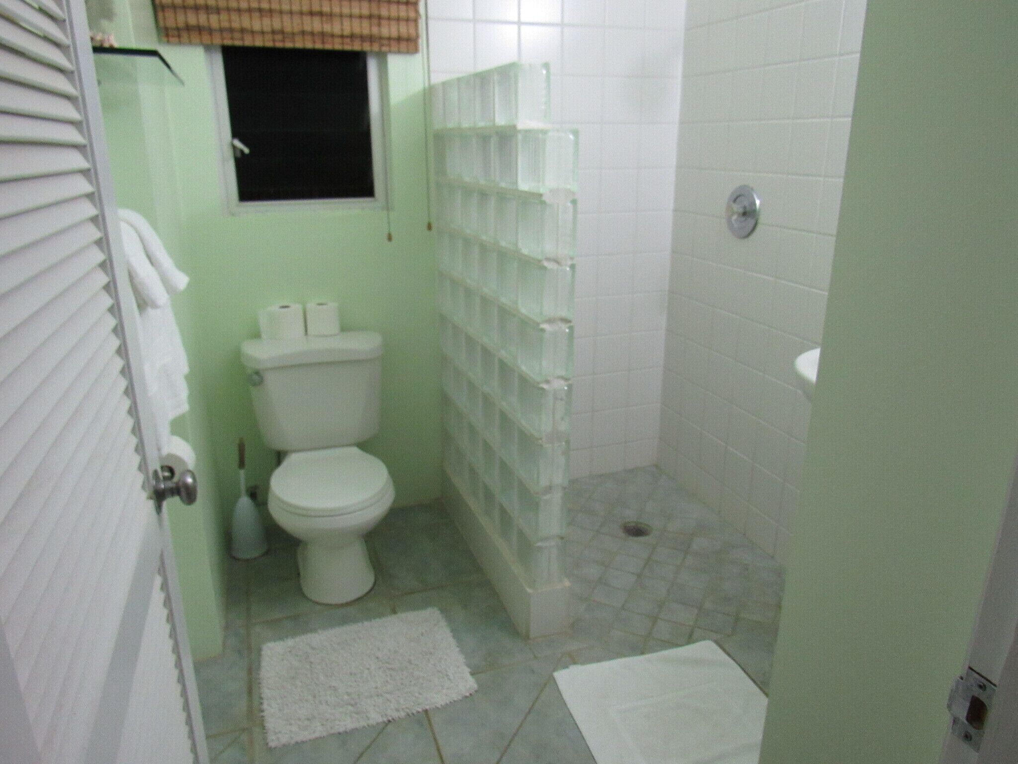 A small bathroom with a toilet, a shower, and a sink.