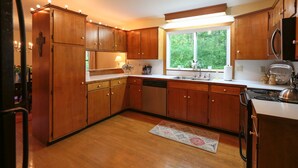 A kitchen with wooden cabinets, a stainless steel sink, a dishwasher, and a stove.