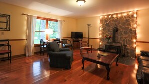 A cozy living room with a stone fireplace, wooden flooring, and comfortable seating.