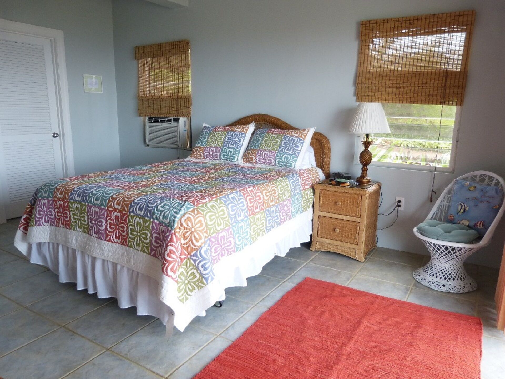 Une chambre à coucher comprenant un lit, une table de chevet, une chaise, une fenêtre donnant sur un paysage agréable et une porte.