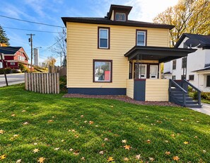 A two-story residential building with a front porch and a visible staircase. - 1st Base Apt 1 - All Star Baseball Rentals (Oneonta)