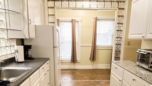 A kitchen with white cabinets, a refrigerator, a coffee maker, and a toaster. - 1st Base Apt 1 - All Star Baseball Rentals (Oneonta)