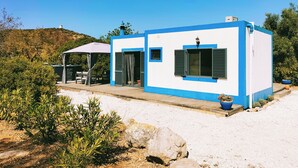 Un petit bâtiment d’un seul étage, à l’extérieur bleu et blanc, doté d’un patio couvert et offrant une vue sur un paysage vallonné.