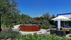 Un bain à remous dans un jardin aménagé, avec un bâtiment moderne en arrière-plan.