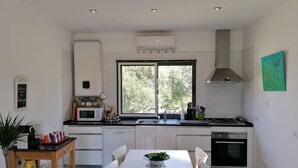 Une cuisine moderne avec des meubles blancs, un four à micro-ondes, un évier et une fenêtre.