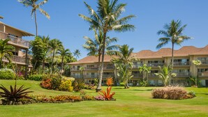 A hotel with multiple floors, a well-maintained lawn, and palm trees.