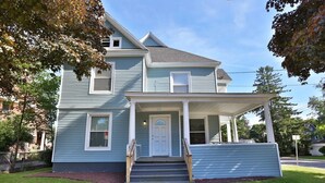 A two-story house with a front porch, a covered entryway, and a visible front door. - 2nd Base Apt 1 - All Star Baseball Rentals (Oneonta)