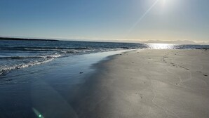 Een strand met een heldere lucht en de zon die schijnt.