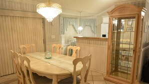 Un coin repas comprenant une table ronde, des chaises en bois, un lustre et un buffet dont les portes sont en verre.