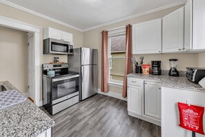 A compact kitchen with a microwave, oven, refrigerator, and granite countertop. - 2nd Base Apt 2 - All Star Baseball Rentals (Oneonta)