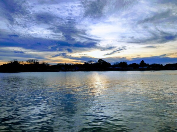 A calm lake with a sunset sky, reflecting the colors of the sky on the water's surface.