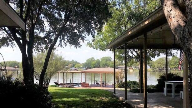 A covered outdoor area with a view of a lake, a gazebo, and a picnic table.