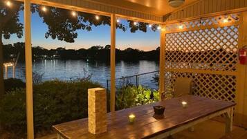 Relax in a serene outdoor seating area surrounded by a body of water, complete with a wooden table and benches.