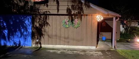 A garage with a basketball hoop, a covered porch, and a decorative wreath on the wall.